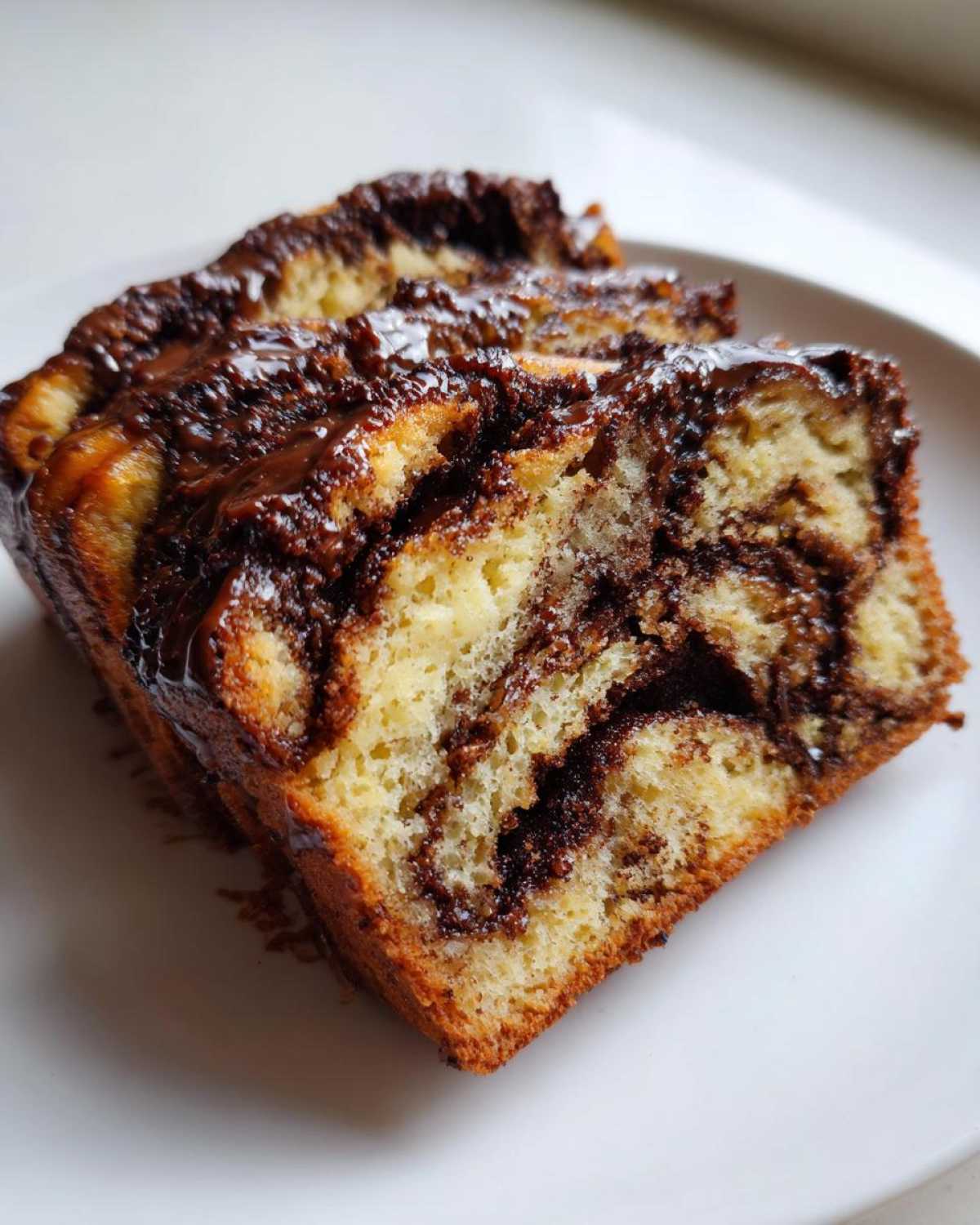 Close-up of three slices of rich chocolate babka showing the beautiful dark chocolate swirls and glossy topping.