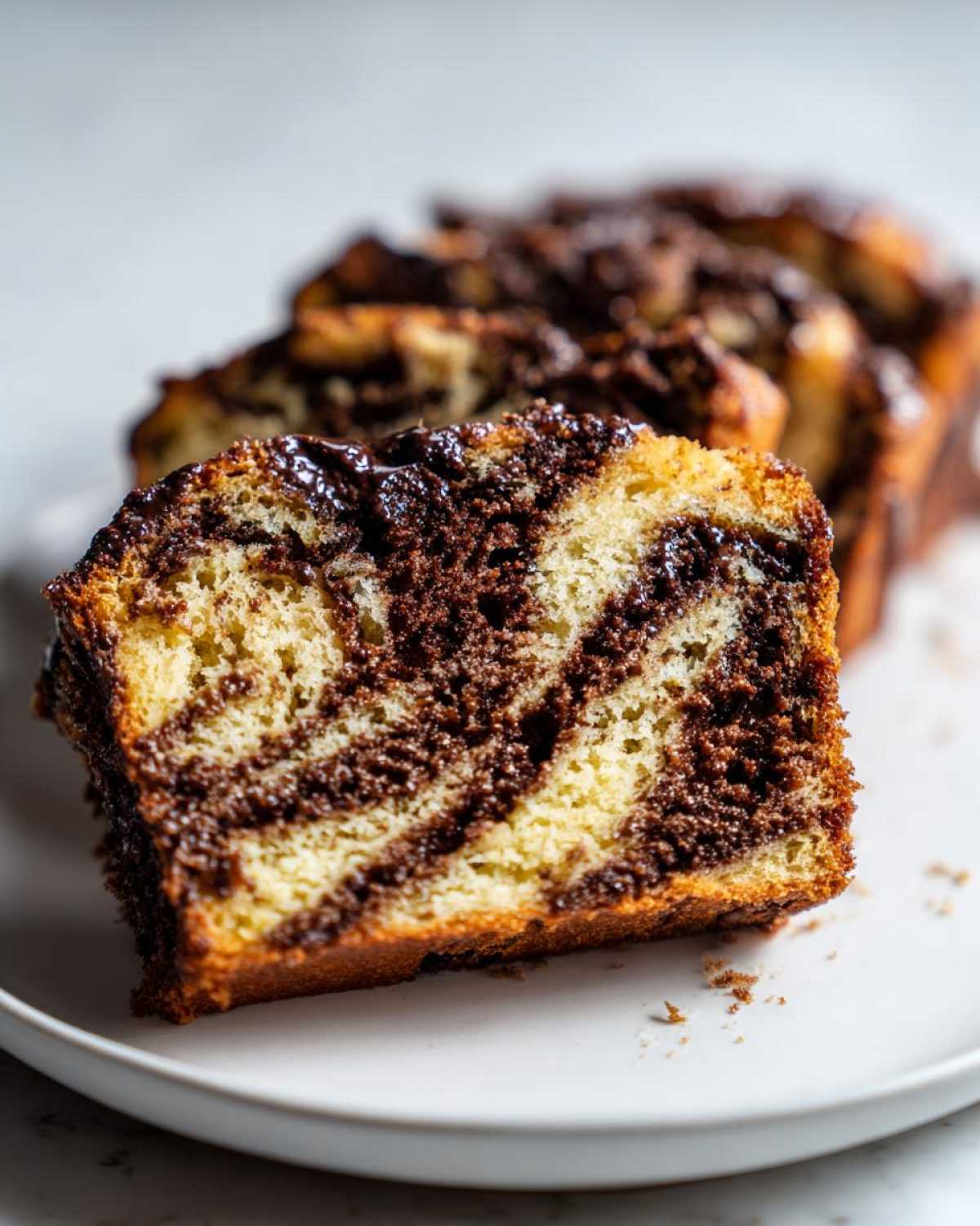 A thick slice of rich chocolate babka showing beautiful dark chocolate swirls against the golden dough.