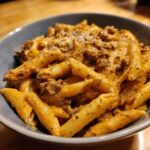 Close-up of creamy beef pasta made with penne noodles coated in a rich, orange sauce with ground beef.