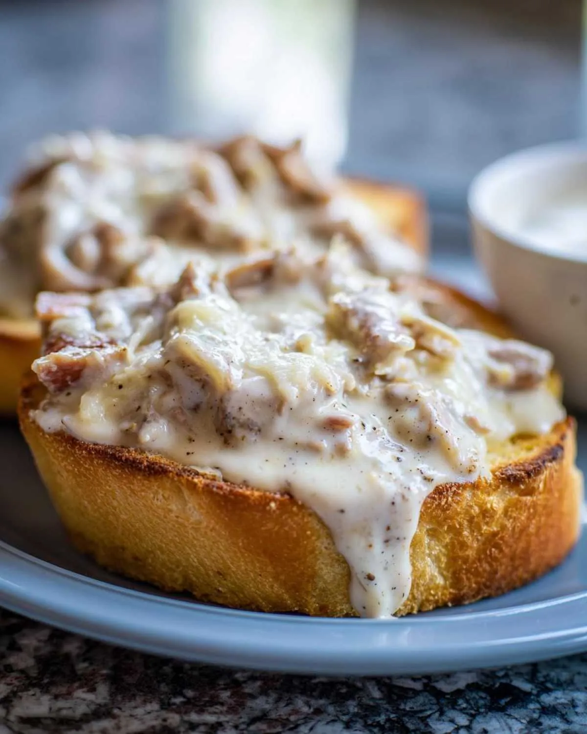 Close-up of creamy chipped beef on toast, featuring thick white gravy dripping down golden toast.