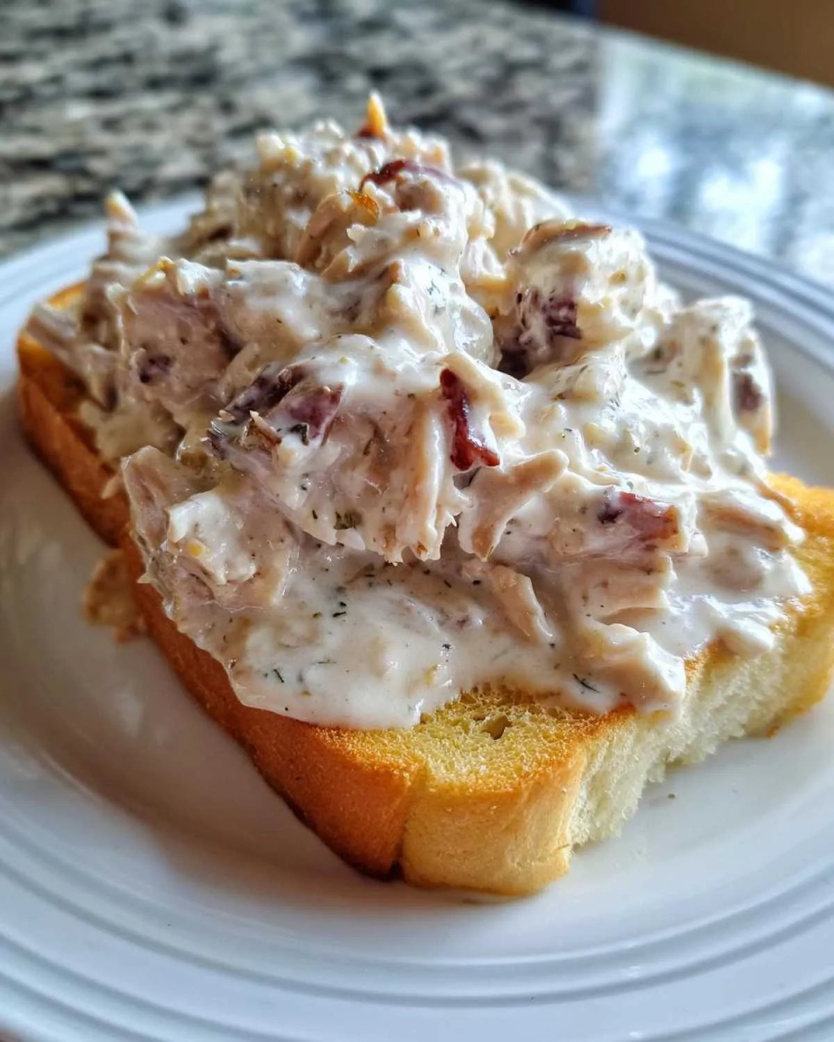 A close-up of creamy chipped beef on toast, featuring shredded meat in a white sauce on toasted bread.