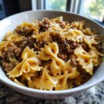 Close-up of creamy parmesan garlic beef bowtie pasta coated in a rich sauce and served in a white bowl.