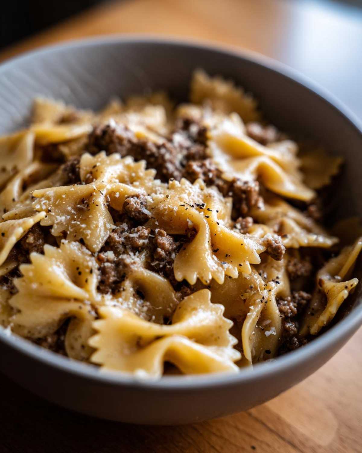 Close-up of creamy parmesan garlic beef bowtie pasta topped with grated cheese and black pepper.