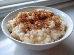 A close-up of a creamy bowl of homemade rice pudding recipe dusted generously with cinnamon.