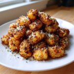 A mound of golden brown, crispy air fryer gnocchi topped with grated Parmesan cheese and parsley.