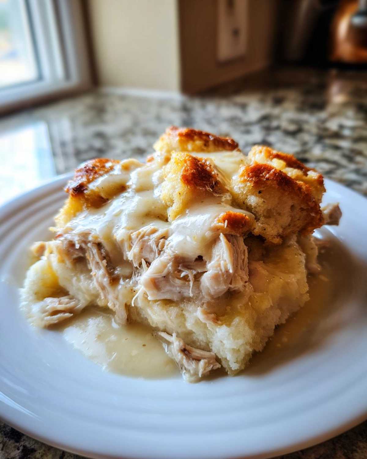 A serving of moist crock pot chicken and stuffing topped with creamy gravy and browned stuffing cubes.
