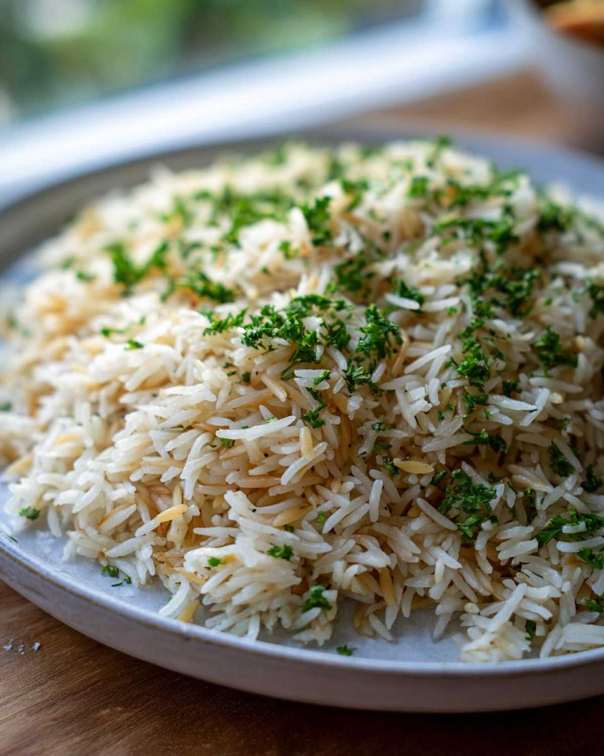 Close-up of fluffy rice pilaf, featuring long grains and toasted vermicelli, garnished generously with chopped fresh parsley.