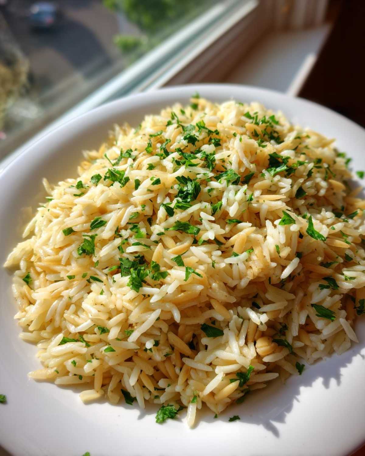 Close-up of fluffy rice pilaf mixed with toasted orzo pasta and topped with fresh chopped parsley.