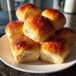 A stack of six fluffy sweet potato rolls with a golden-brown, glossy top sprinkled with coarse sugar.