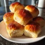A stack of six fluffy sweet potato rolls with a golden-brown, glossy top sprinkled with coarse sugar.