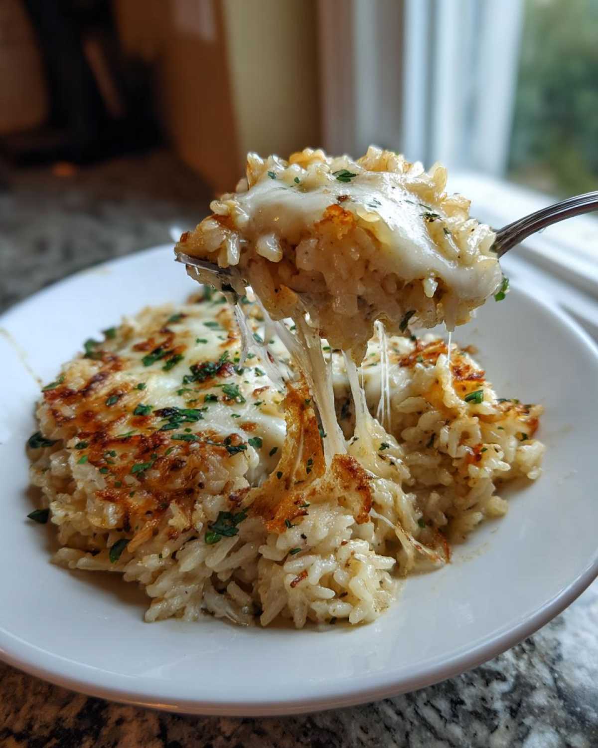 A fork lifts a cheesy, gooey bite of french onion butter rice from a white bowl.