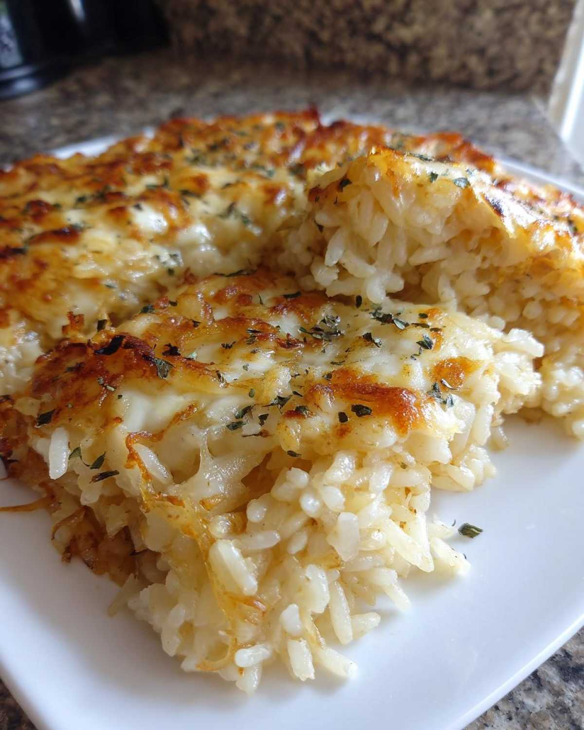 A close-up of a serving of french onion butter rice, topped with melted, browned cheese and herbs.