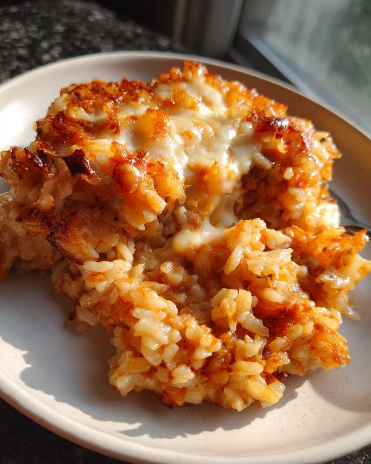 Close-up of a serving of cheesy french onion butter rice with a golden-brown, slightly crispy top.