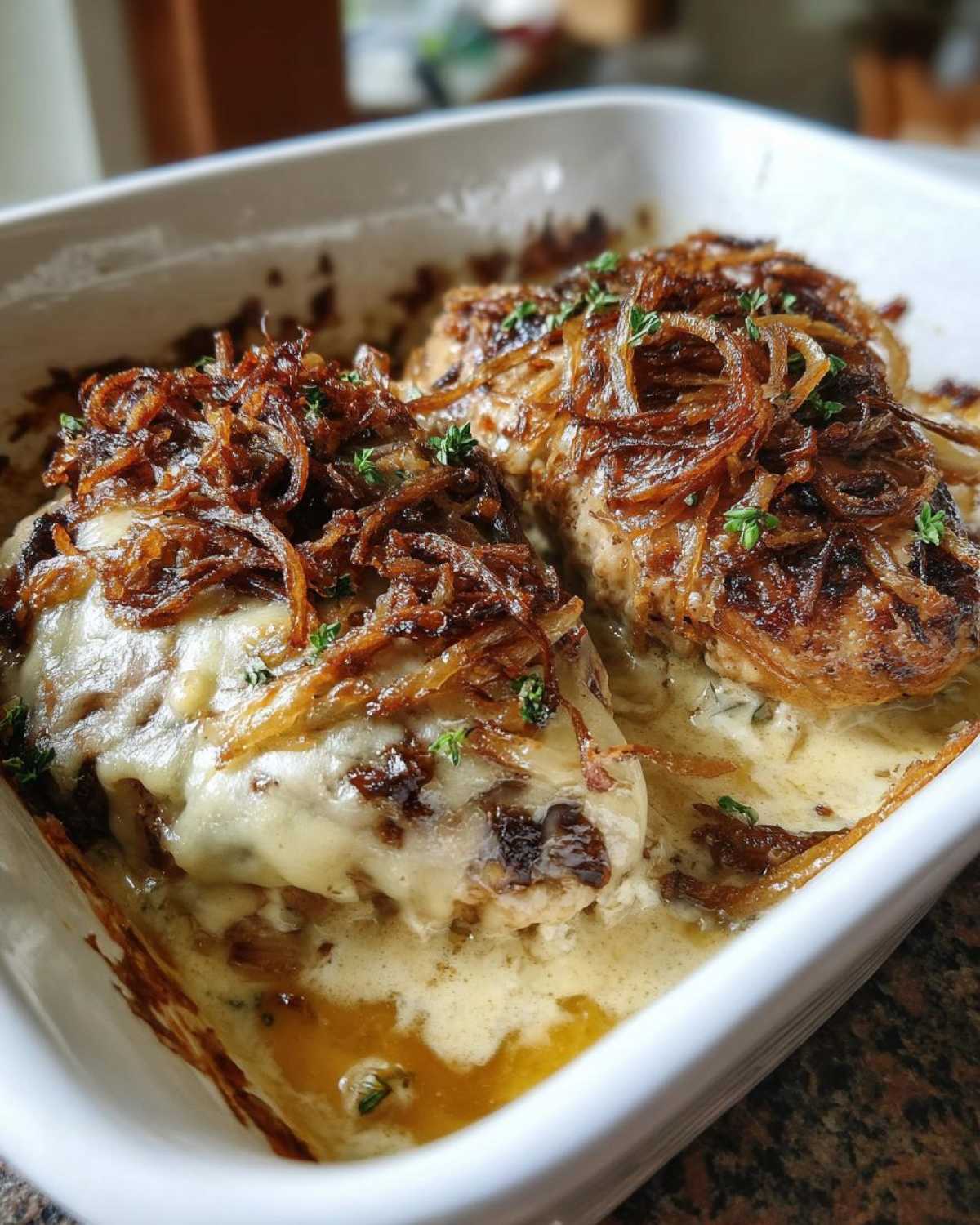 Two pieces of baked french onion chicken covered in melted cheese and crispy fried onions.