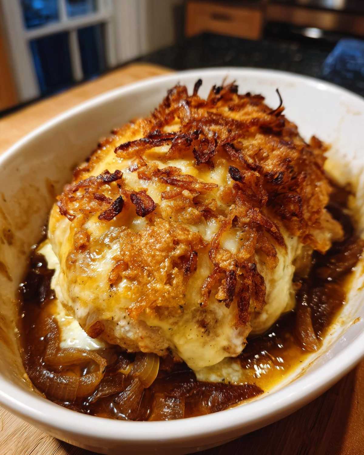 Close-up of french onion chicken topped with melted cheese and crispy fried onions.