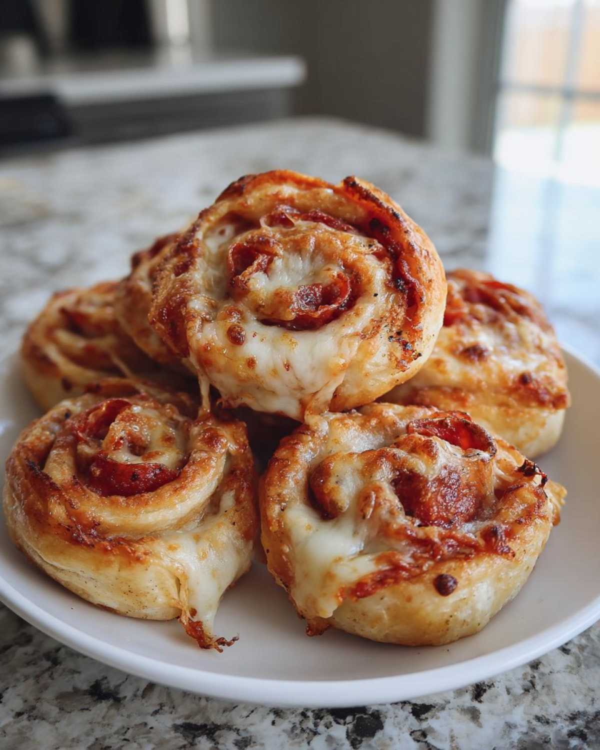 A stack of freshly baked pizza pinwheels with melted mozzarella cheese and pepperoni.