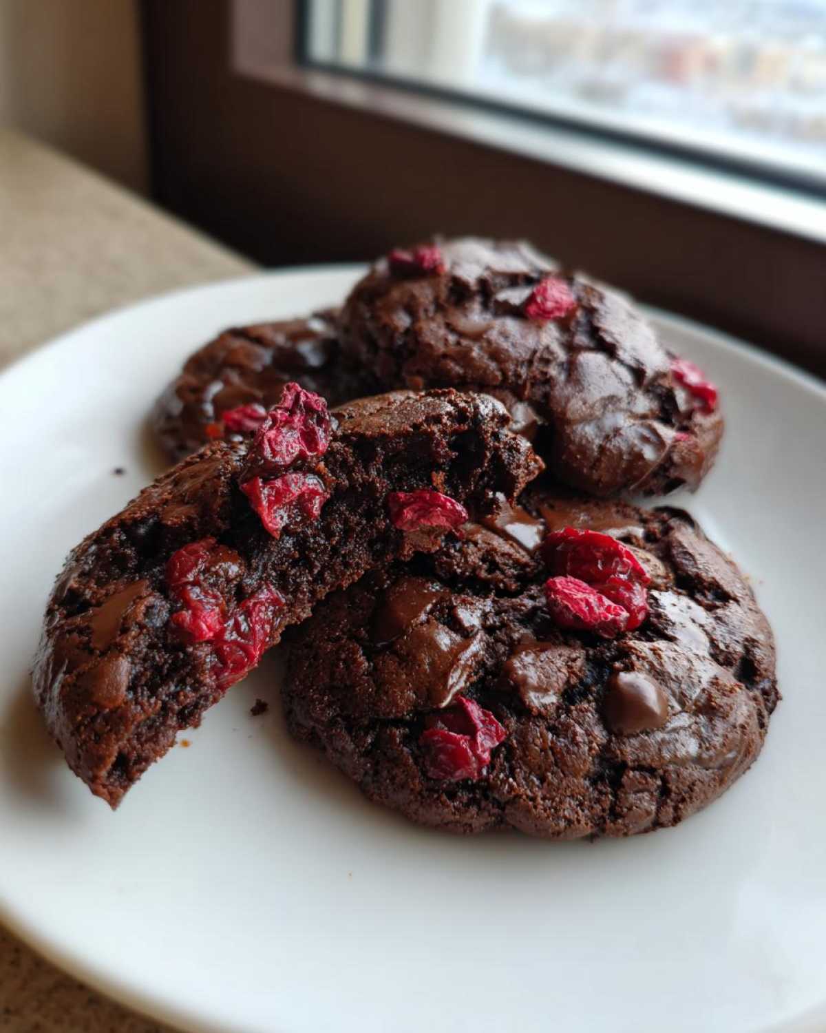 Close-up of fudgy chocolate cherry cookies, one broken open to show the soft interior and dried cherries.