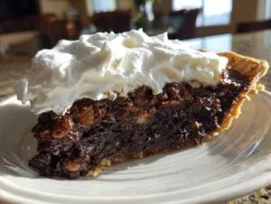 A decadent slice of german chocolate pie featuring a rich, dark filling and topped generously with fluffy white whipped cream.