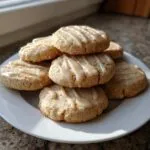 A stack of freshly baked maple cookies drizzled with a light brown glaze, resting on a white plate.