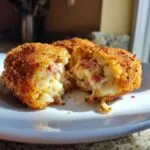 Close-up of golden brown potato croquettes, one cut open revealing a creamy interior with ham pieces.
