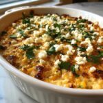 Close-up of baked mexican street corn dip topped with crumbled white cheese and fresh cilantro.