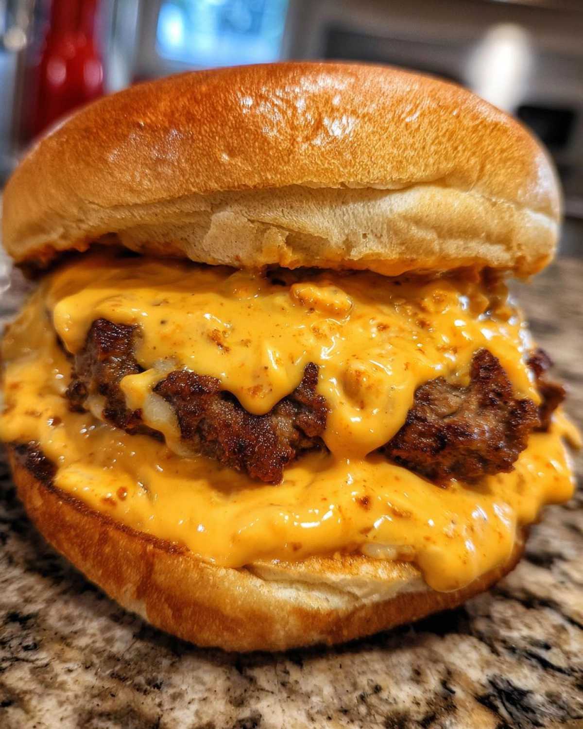 Close-up of a double patty burger generously covered in orange, creamy big mac sauce on a toasted bun.