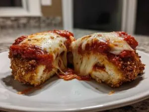 Close-up of keto chicken parmesan cut in half showing melted mozzarella cheese pull and crispy coating.