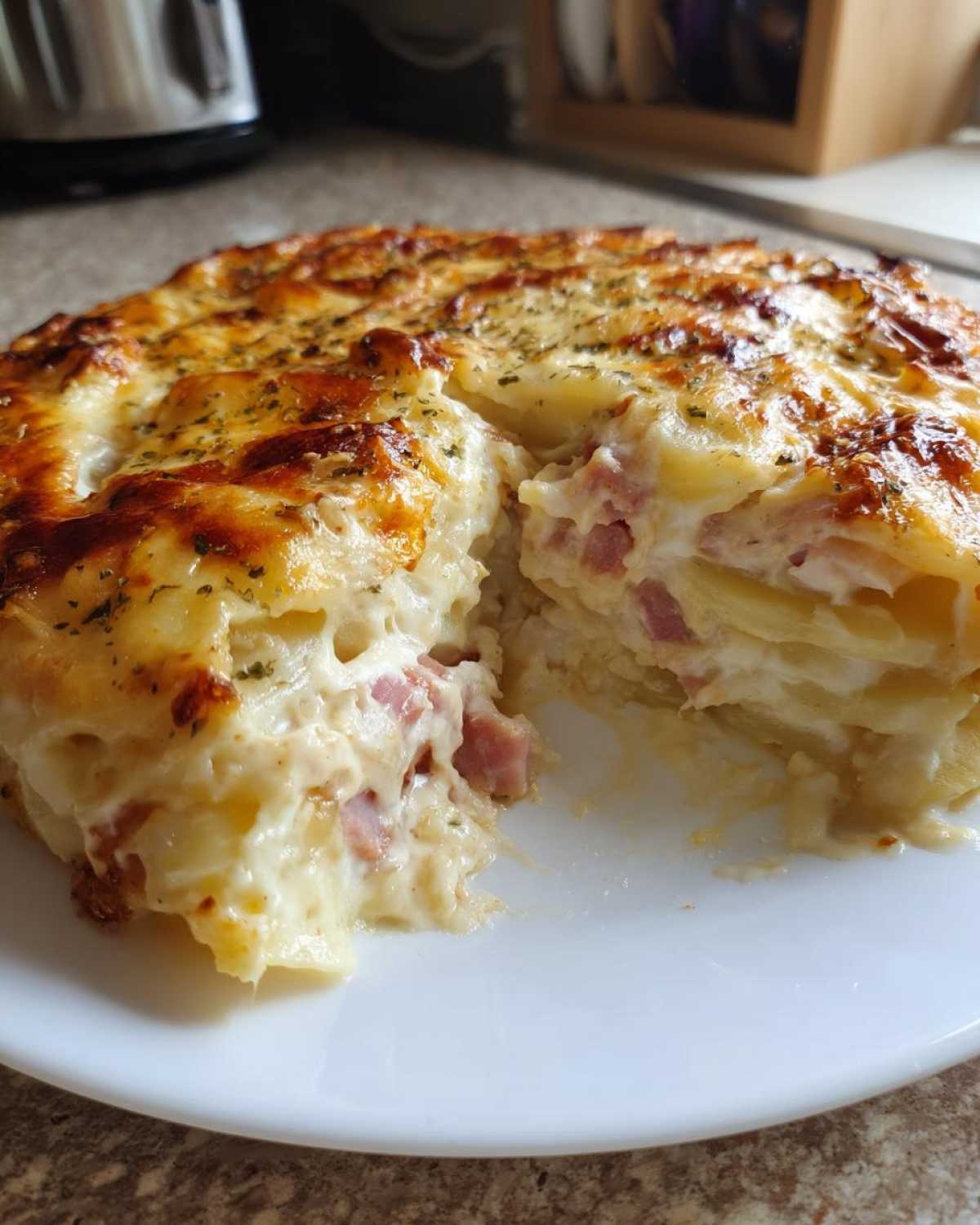Close-up of a serving of layered scalloped potatoes and ham with a creamy sauce and browned cheese crust.