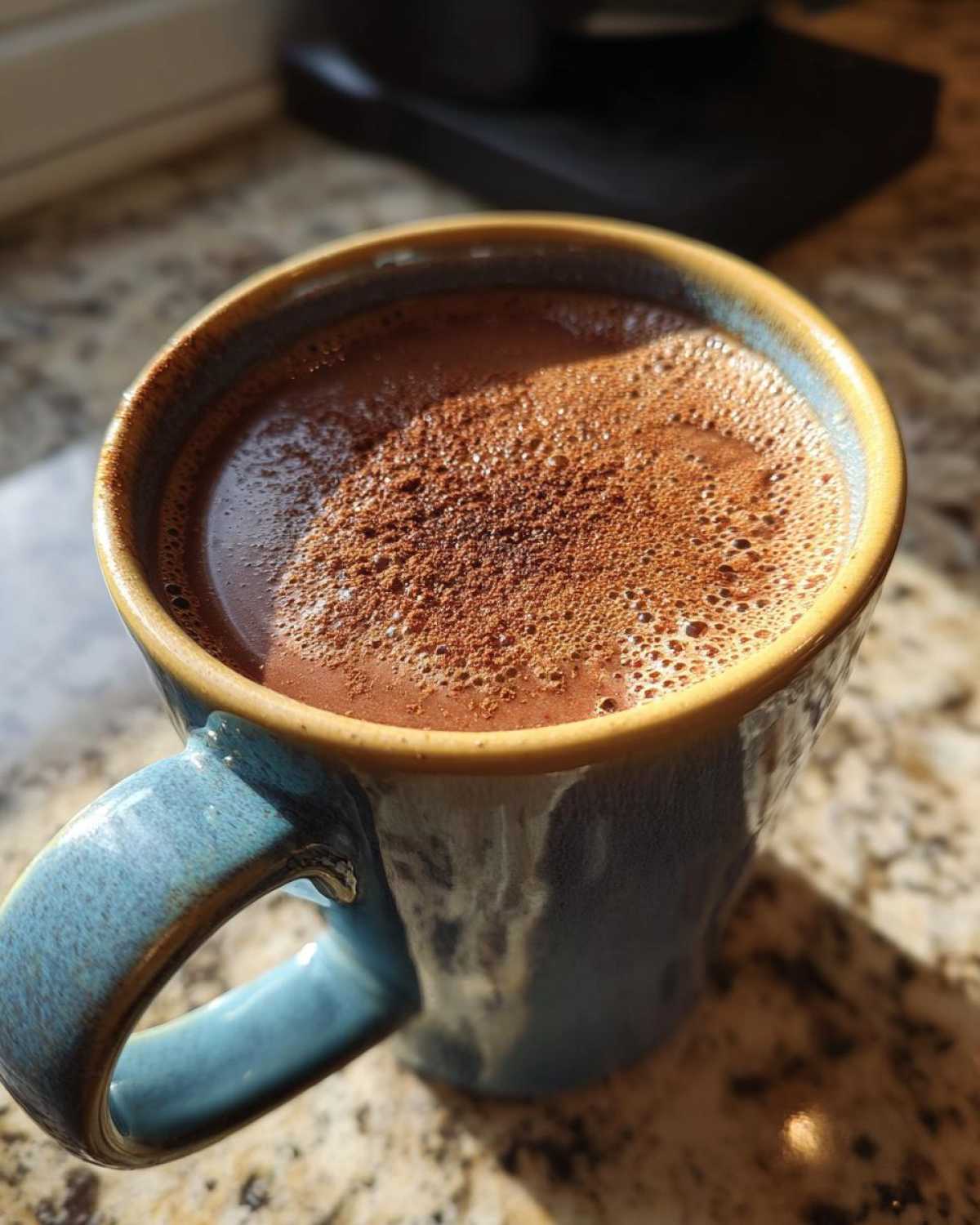 Close-up of a steaming mug of Mexican hot chocolate topped with cocoa powder.