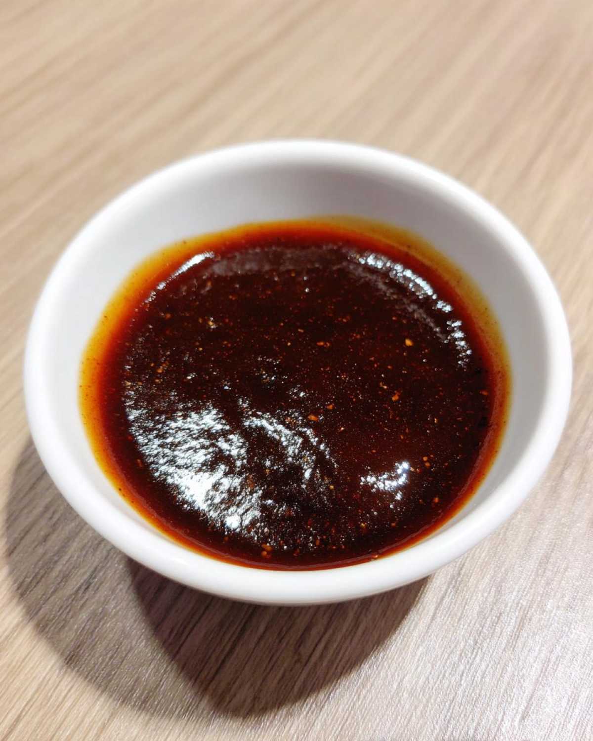 Close-up of thick, dark red homemade bbq sauce in a small white dipping bowl.