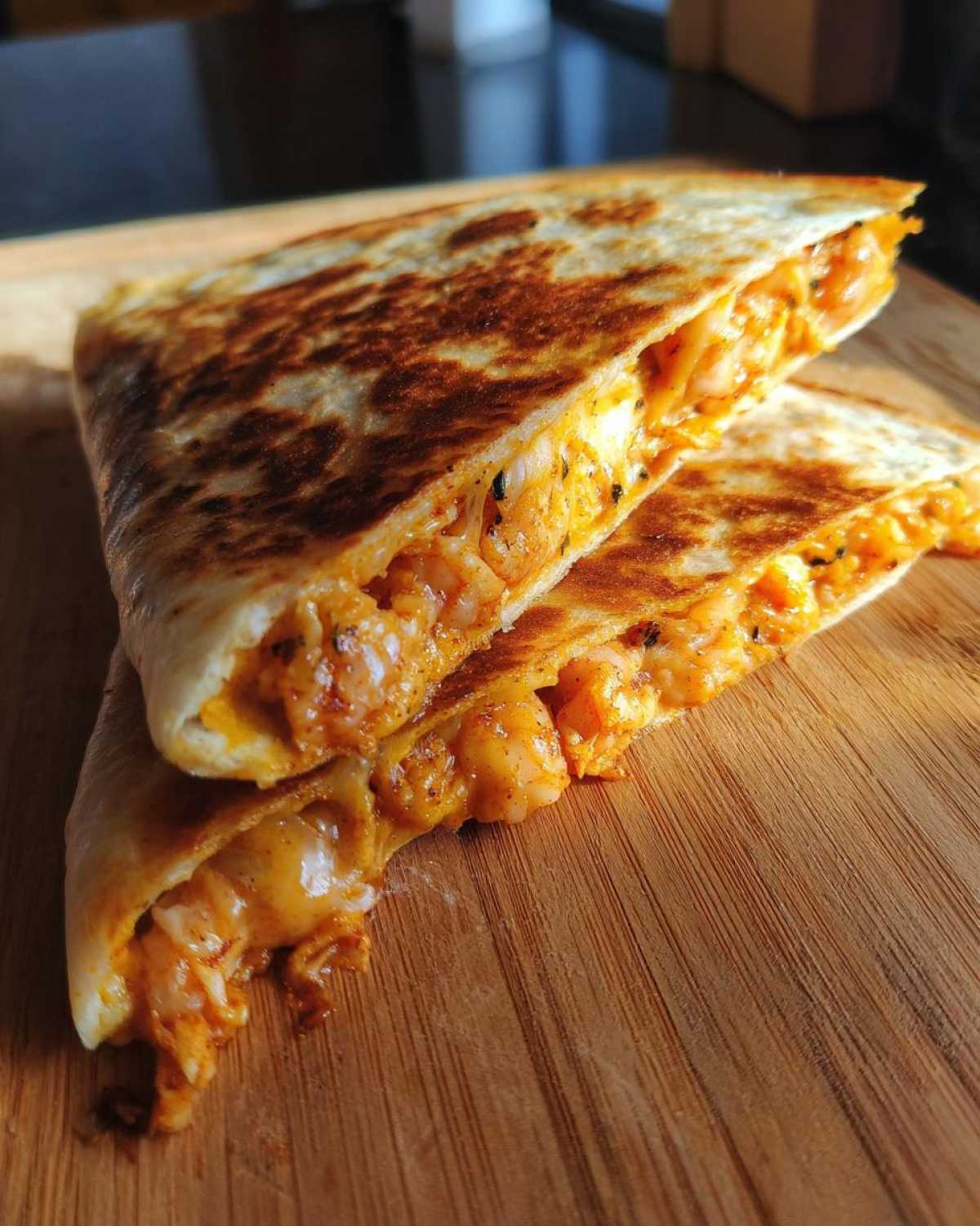 Close-up of a perfectly grilled shrimp quesadilla cut in half, showing melted cheese and seasoned shrimp filling.