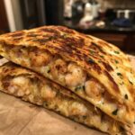 Close-up of a perfectly grilled shrimp quesadilla cut in half, showing melted cheese and seasoned shrimp filling.