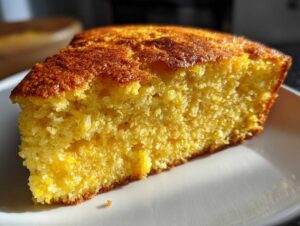 Close-up of a thick, moist slice of bright yellow skillet cornbread with a deeply browned, crisp top.