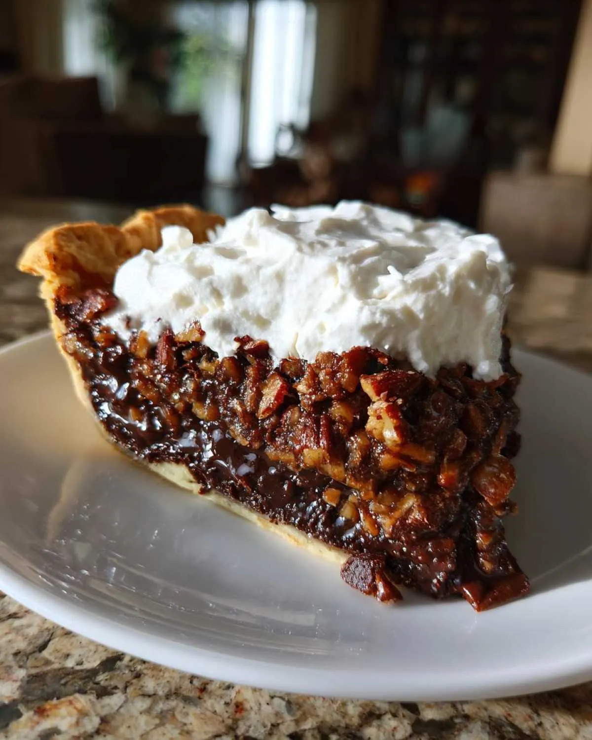 A decadent slice of german chocolate pie featuring a dark chocolate filling, pecans, and a generous topping of whipped cream.