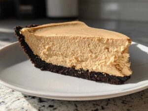 A thick slice of creamy no bake peanut butter pie featuring a fluffy filling and a dark chocolate cookie crust.