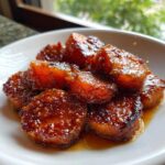 Close-up of sweet potato slices coated in a thick, glossy, caramelized glaze, representing perfect southern candied yams.