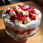 Close-up of a delicious strawberry shortcake trifle layered with whipped cream, macerated strawberries, and pound cake cubes.