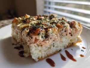 A thick, square slice of baked salmon sushi bake casserole served on a white plate.