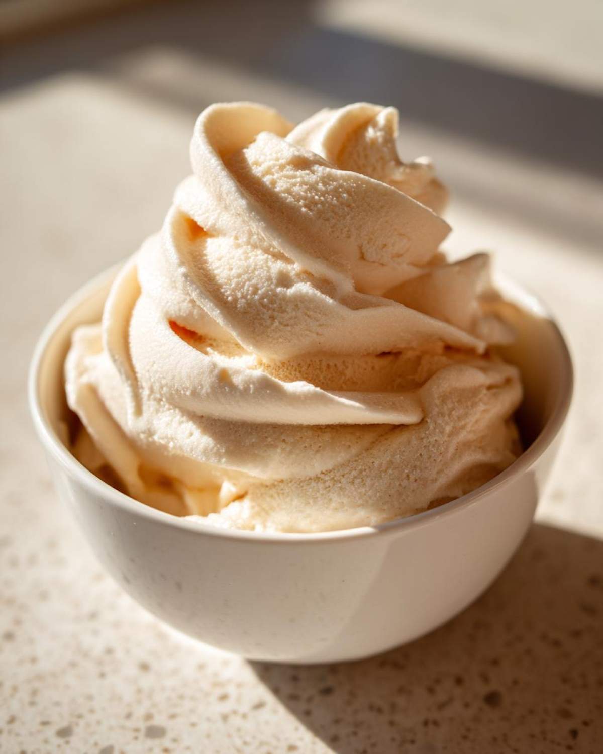 A close-up of creamy, swirled banana ice cream served in a small white bowl.