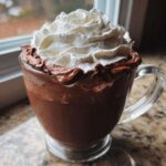 A rich, dark chocolate beverage topped with thick whipped hot chocolate foam and whipped cream.