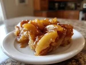 A close-up shot of a serving of rich, glossy apple pie filling with cinnamon spices on a white plate.