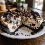 A decadent slice removed from a no-bake oreo pie, showing the creamy filling and dark chocolate crust.