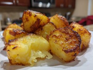 Close-up of perfectly golden and crispy roast potatoes showing a fluffy interior texture.