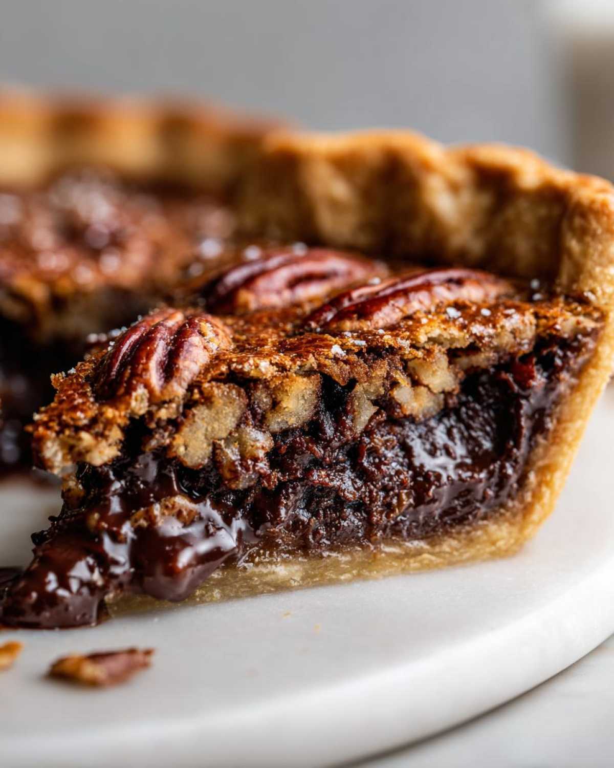 Close-up of a slice of chocolate bourbon pecan pie showing the gooey chocolate filling and pecan topping.