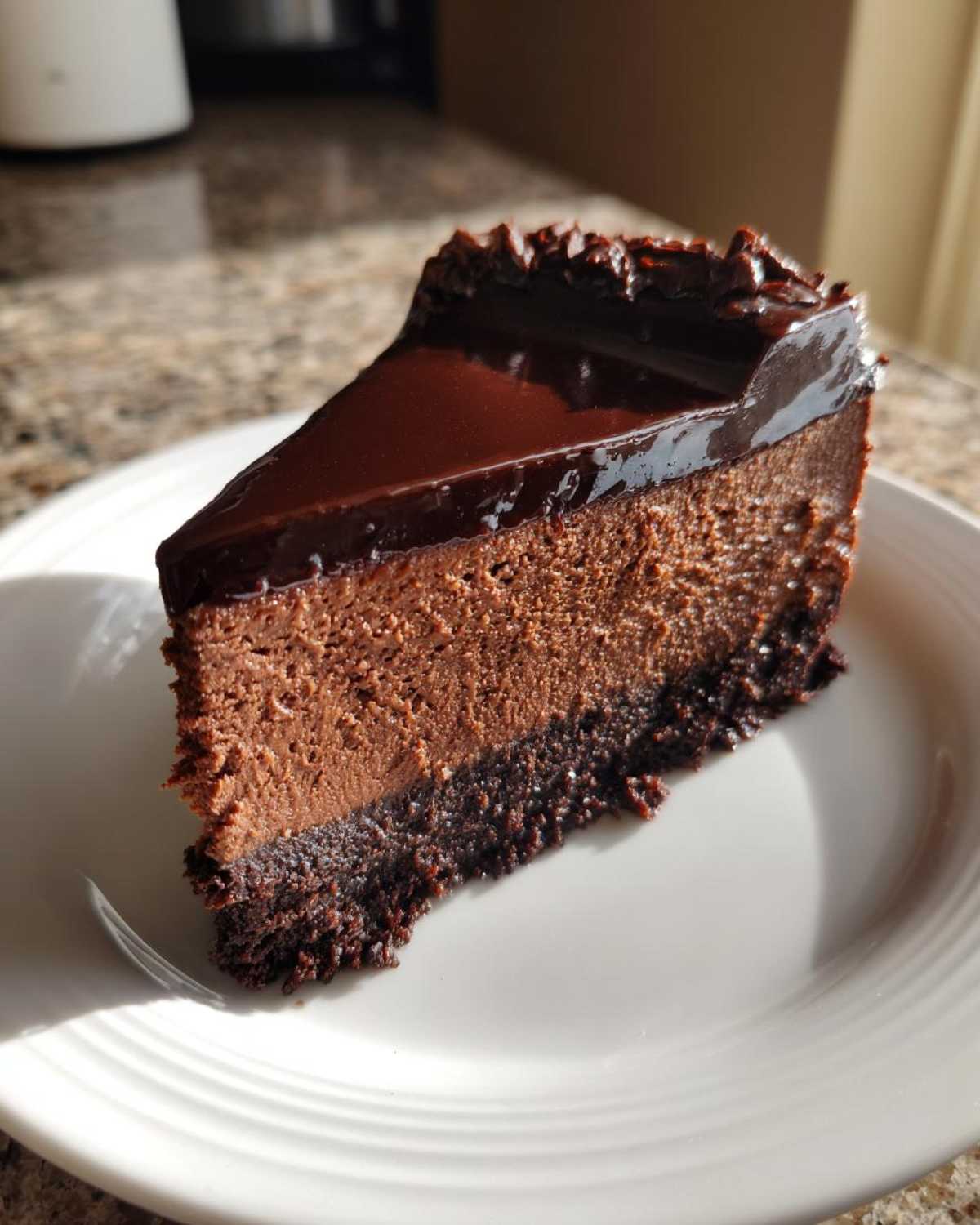 A perfect slice of rich chocolate cheesecake with a dark chocolate crust and glossy ganache topping.