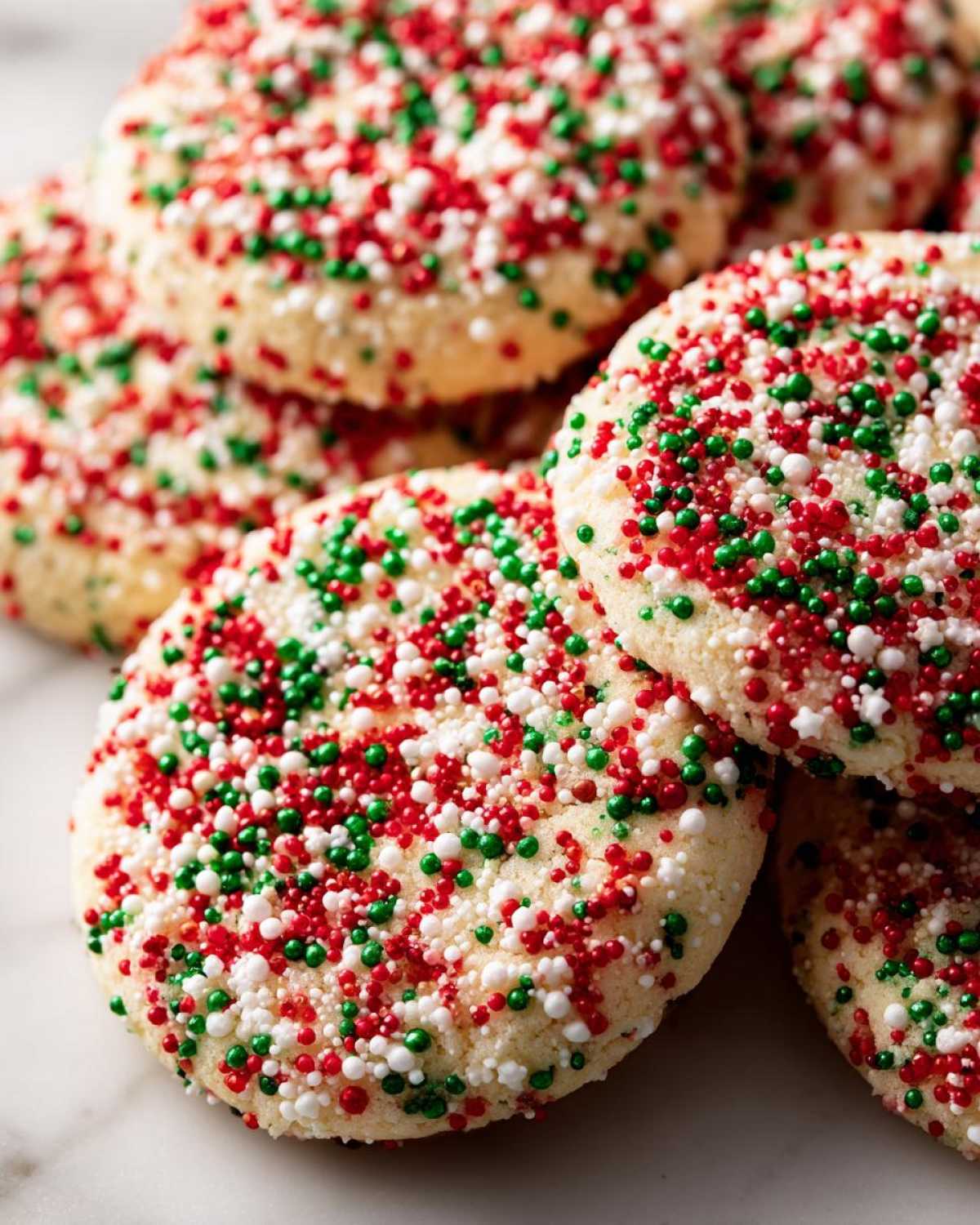 Close-up of several soft christmas sprinkle sugar cookies topped with festive red, green, and white nonpareils.