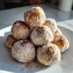 A tempting pile of freshly made cinnamon sugar snowball cookies coated in a thick layer of sugar and spice.