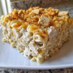 A generous slice of creamy chicken noodle casserole topped with melted cheese, herbs, and croutons.