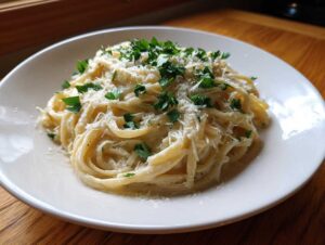 A close-up of creamy pasta coated in a rich sauce, topped with grated parmesan and fresh parsley, representing garlic parmesan comfort food.