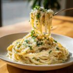 A fork lifting creamy pasta coated in sauce, topped with grated cheese and fresh parsley, representing a delicious garlic parmesan dish.